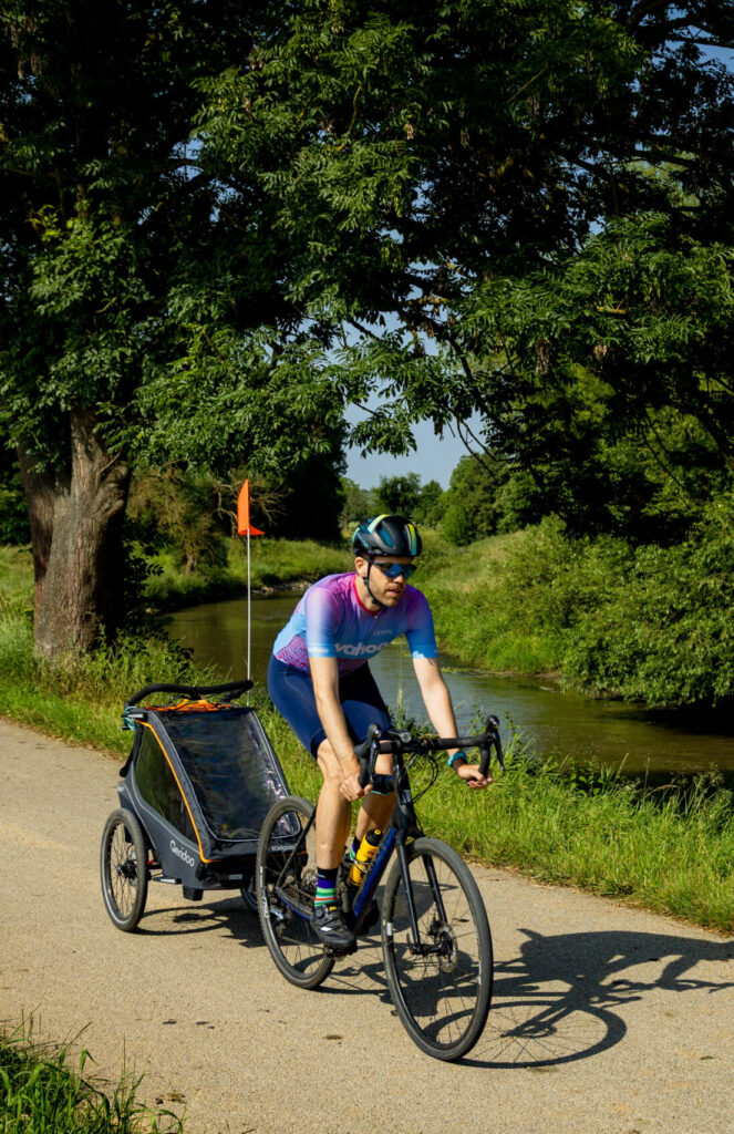 15-DH8A4795 Konstantin (The Cycling Dad) riding riverside trail with Qeridoo Kidgoo 1 bike trailer near trees and greener