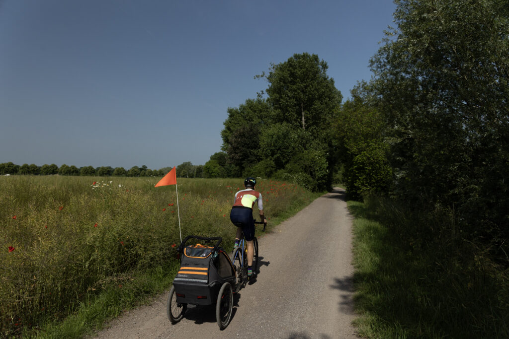 Konstantin (aka The Cycling Dad) with Qeridoo Kidgoo 1 trailer on country grvael road wirh a big field of poppies on the left ahnd side