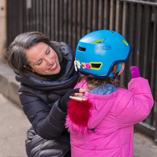 Woman adjusting ablue kids helmet at her kid