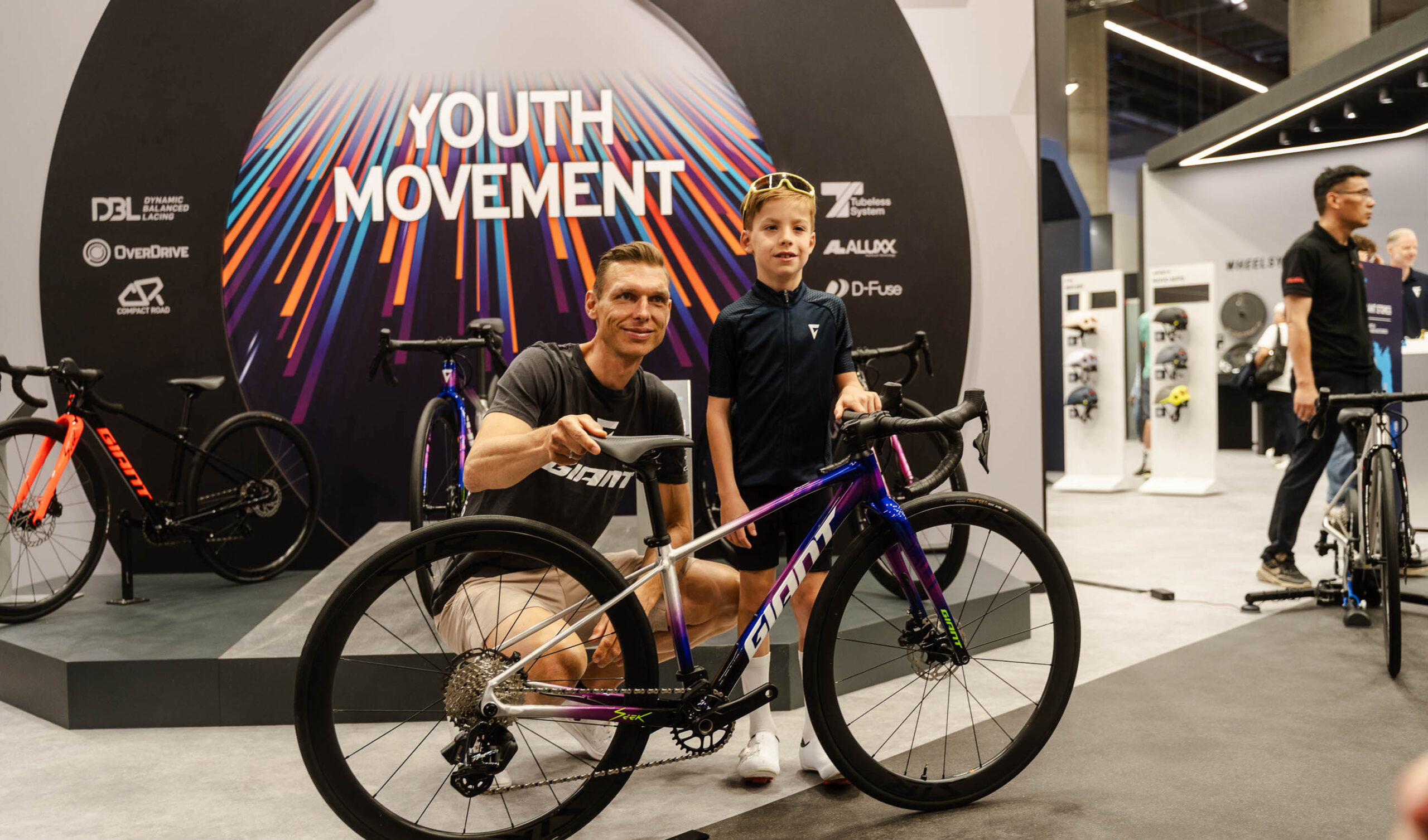 Former pro Tony Martina and a kid posing next to the new Giant seek, a road race bike for kids.