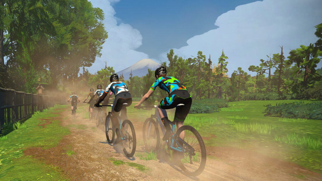 Group of Zwift riders on mountain bikes riding a dirt trail with Mount Fuji in the distance.
