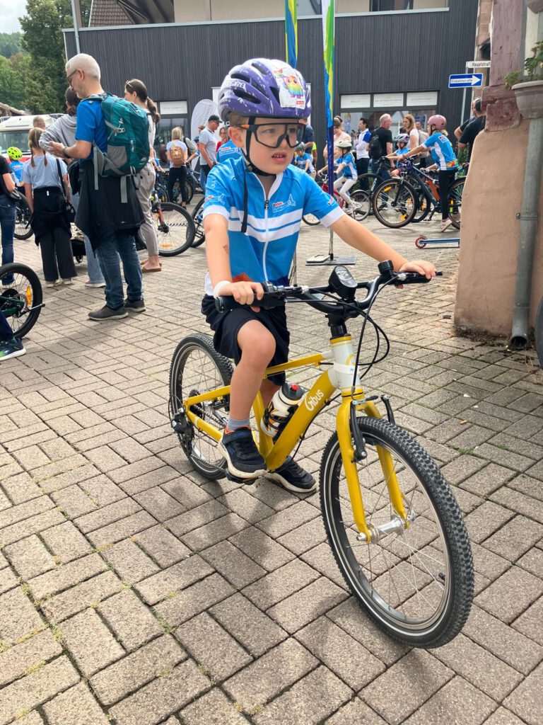 DTour-BadOrb-2026-jersey Focused young rider before start of the Joy of Moving Mini Tour Bike Parade.